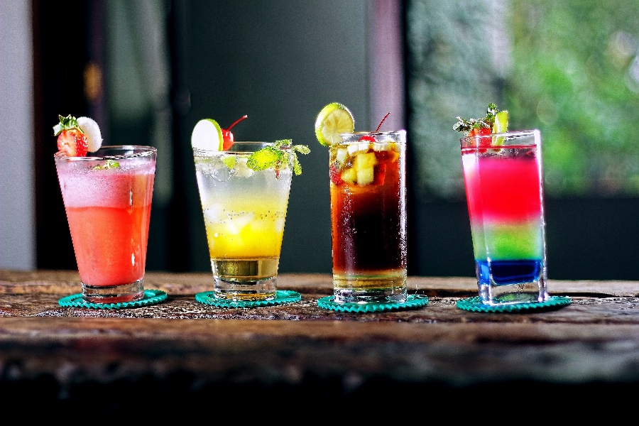 Apsveikuma e-kartiņa Četras krāsainas alkohola glāzes uz galda