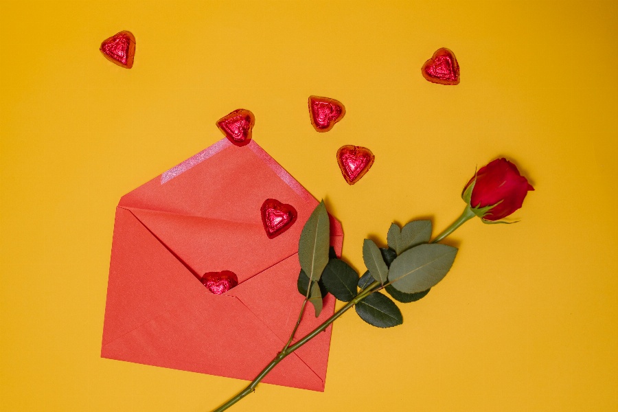 Apsveikuma e-kartiņa Sarkans konverts ar sirsniņām un sarkanu rozi uz dzeltena fona