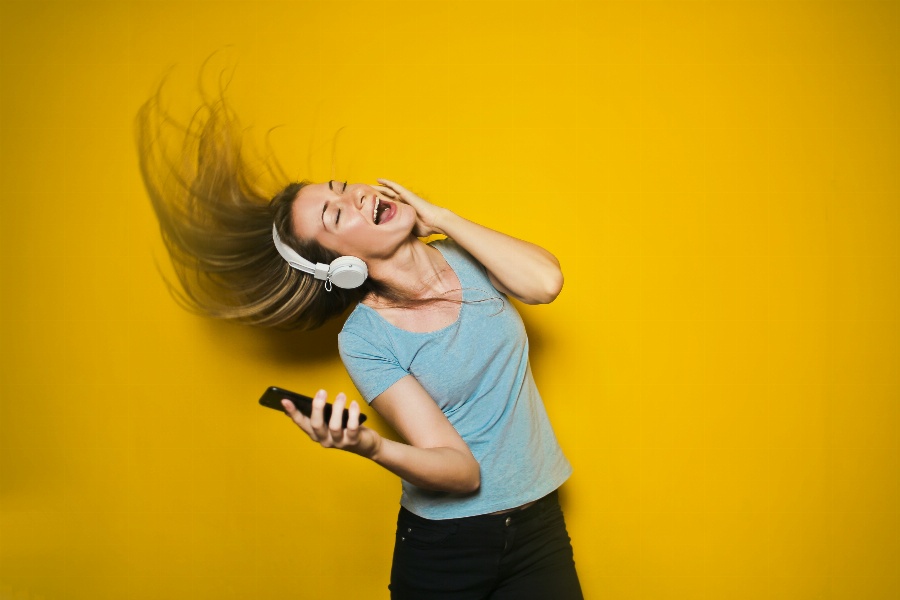 Apsveikuma e-kartiņa Sieviete dzied klausoties mūziku uz austiņām
