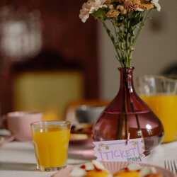 Brokastu galds ar sulas glāzi un puķēm vāzē