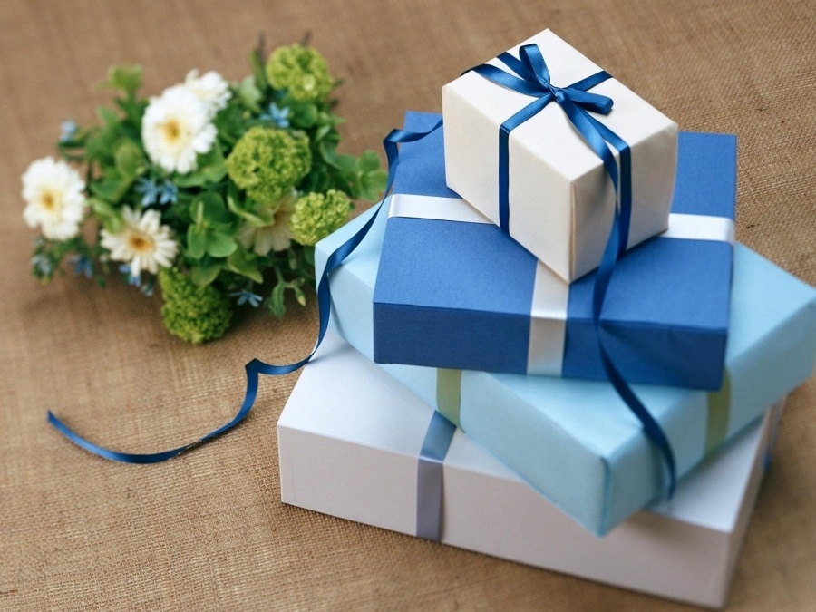 Apsveikuma e-kartiņa Zilas dāvanu kastītes blakus ziediem uz galda